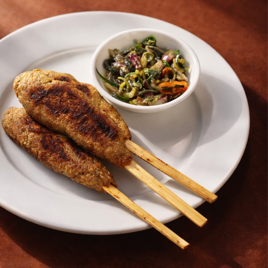 Three skewered chicken dishes on a white plate with a side of salad.