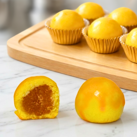 Yellow pineapple tart pastries on a wooden board with one cut open on a marble surface