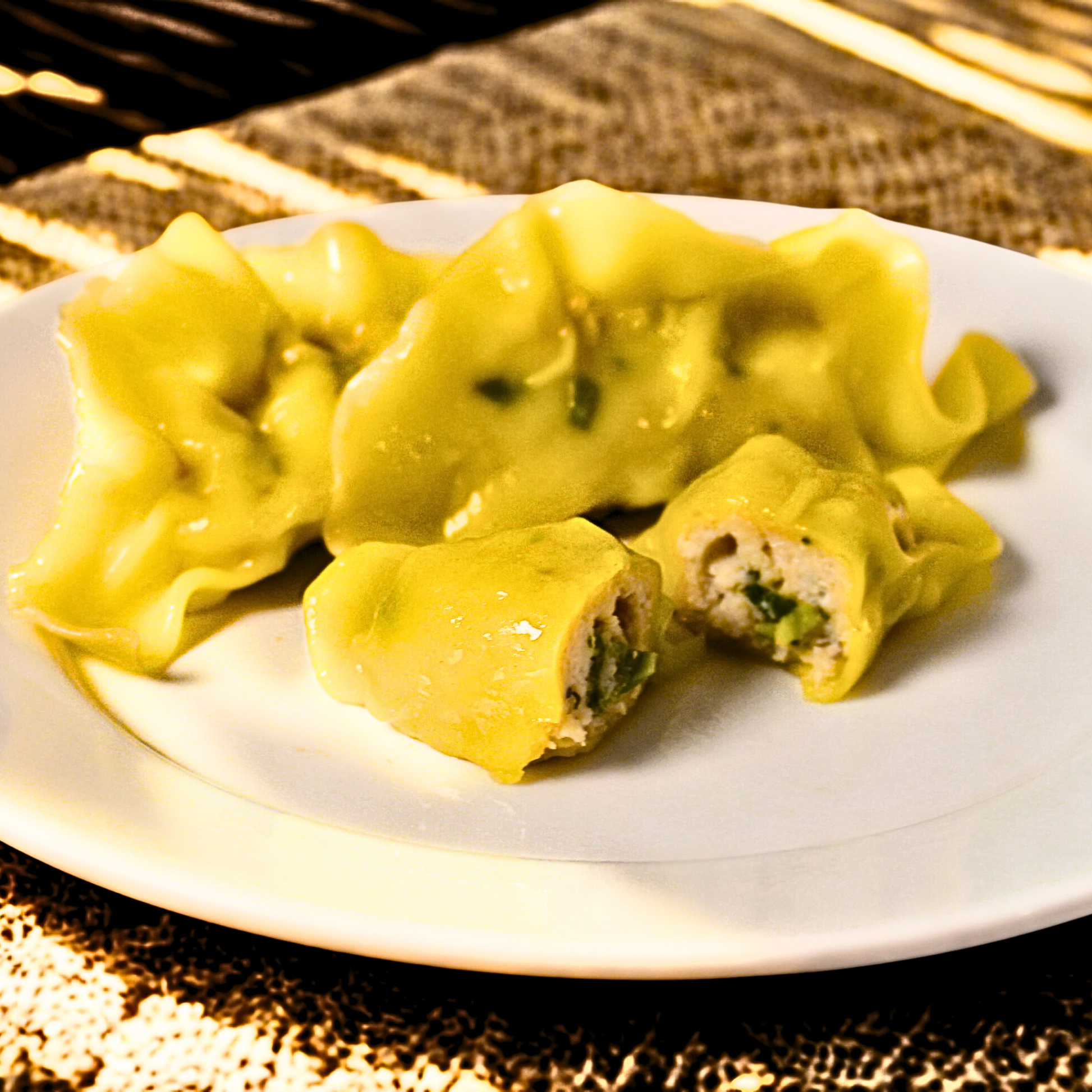 Upclose of chicken dumplings on a white plate with a gold and brown patterned tablecloth.