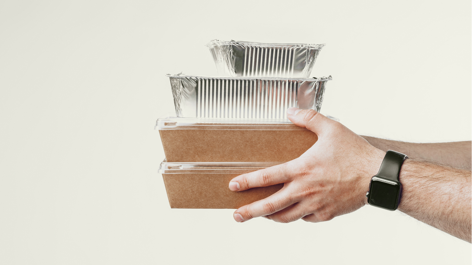 Hand holding a stack of cardboard boxes with metal containers on a light background
