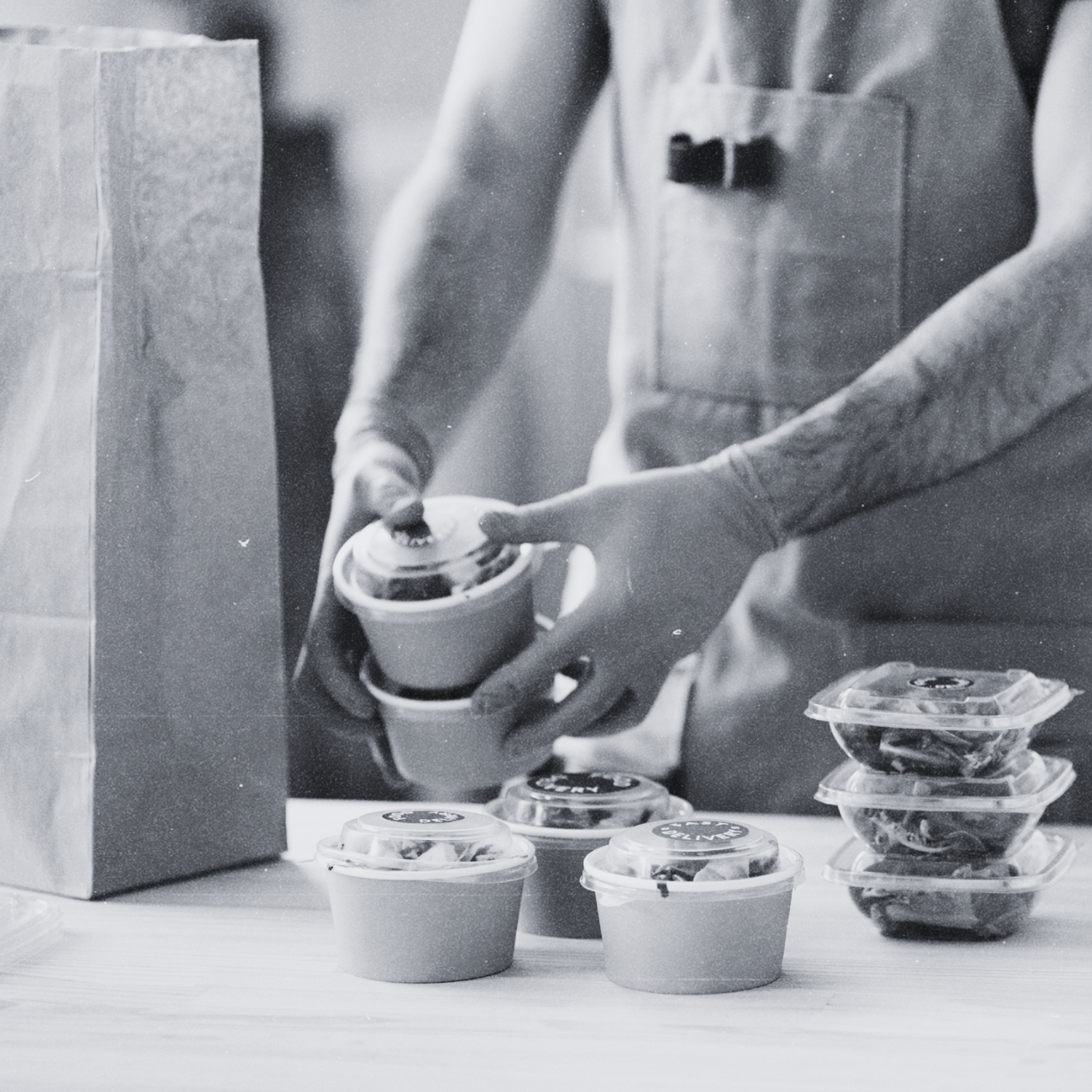 Person packaging food items into containers on a table.